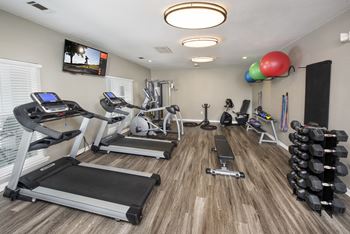 a gym with cardio machines and weights and a tv